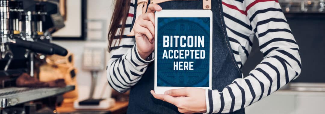 Woman holding tablet we accept bitcoin on screen